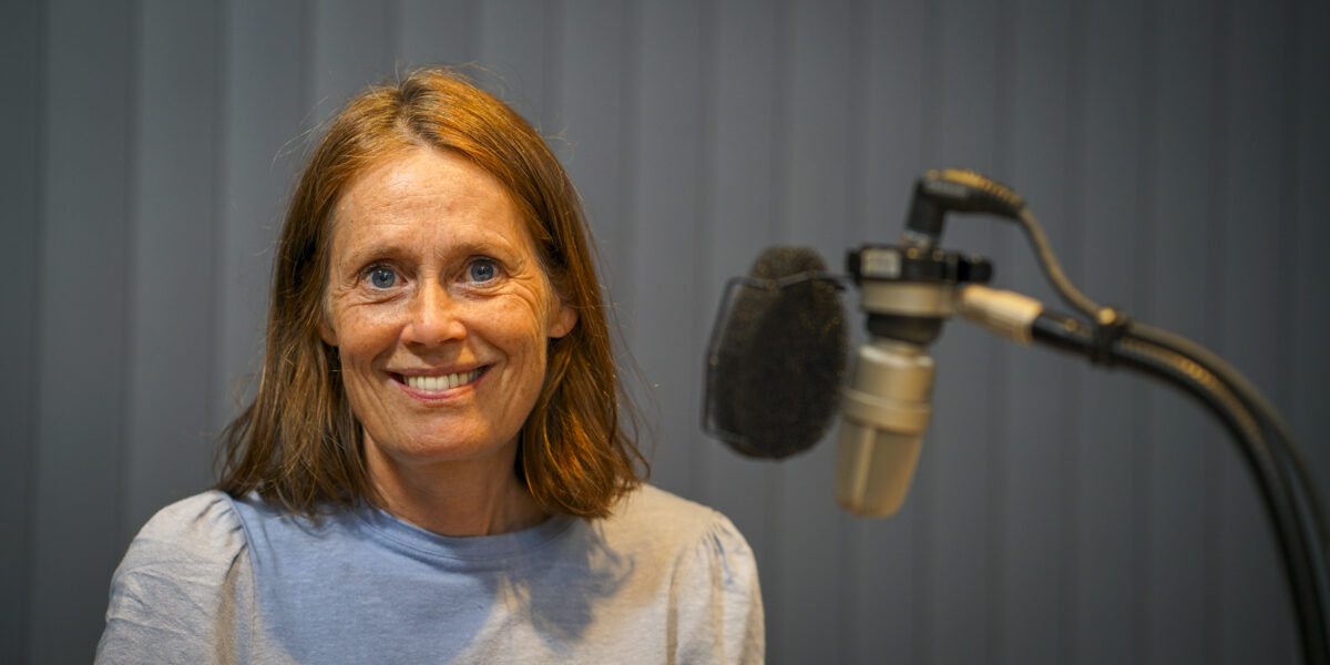 Kvinne sitter foran en mikrofon.